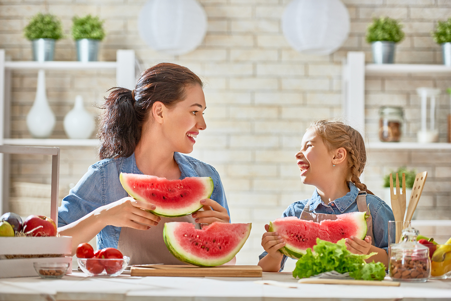 Healthy food at home. Happy family in the kitchen. Mother and child daughter are preparing the vegetables and fruit.