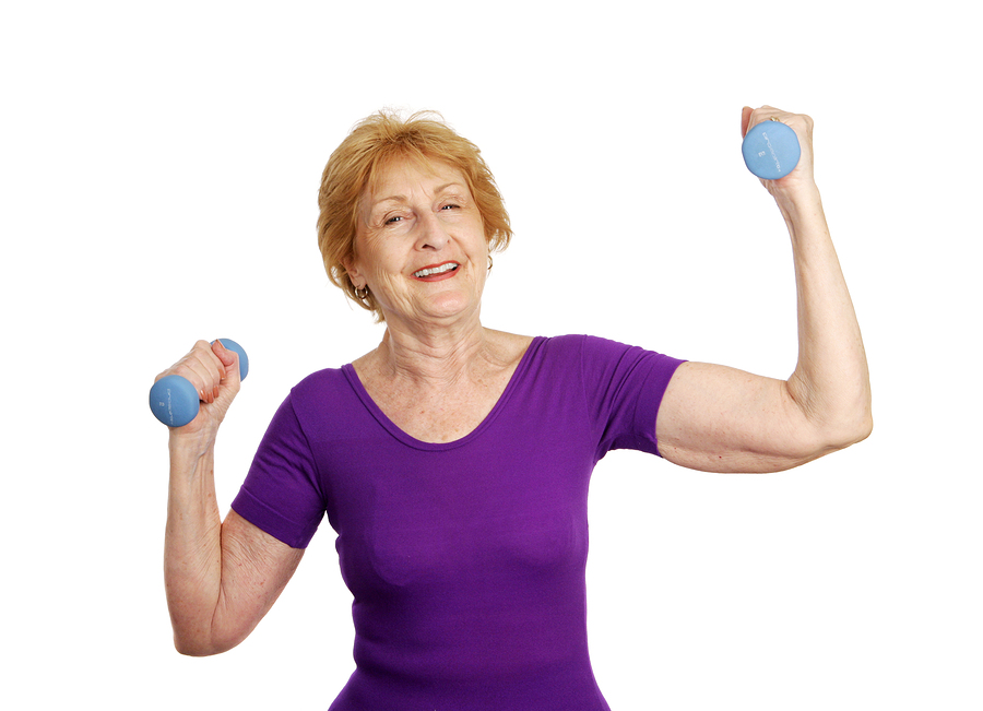 A pretty senior woman smiling as she lifts freeweights. Isolated on white.